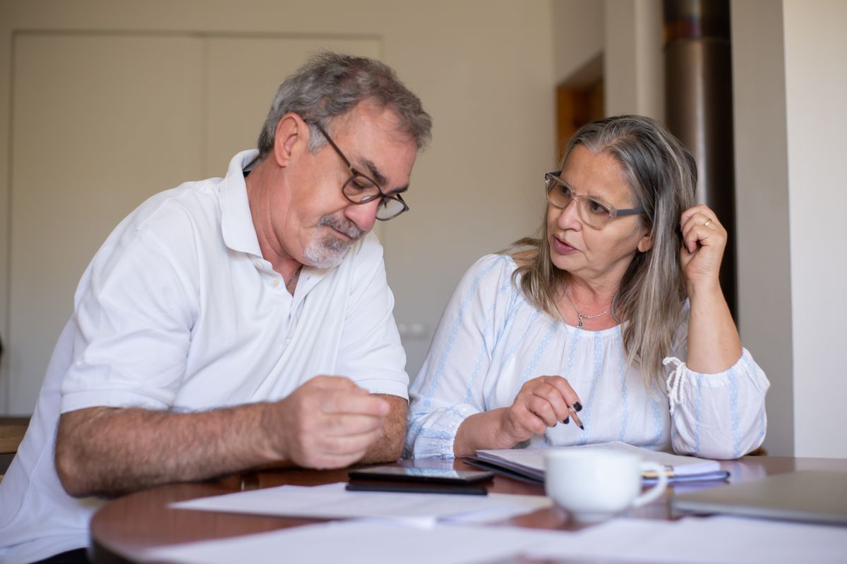 Direito Previdenciário Internacional: Guia de Acordos 2026 3 Casal de idosos preenchendo documentos sobre a mesa, representando a comprovação de tempo de contribuição e a totalização de períodos previdenciários